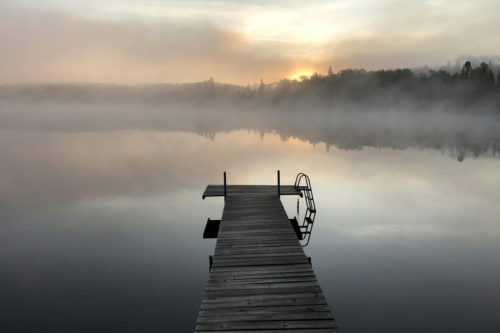 Short Dock Cottages. A dock in morning mist on a still lake.