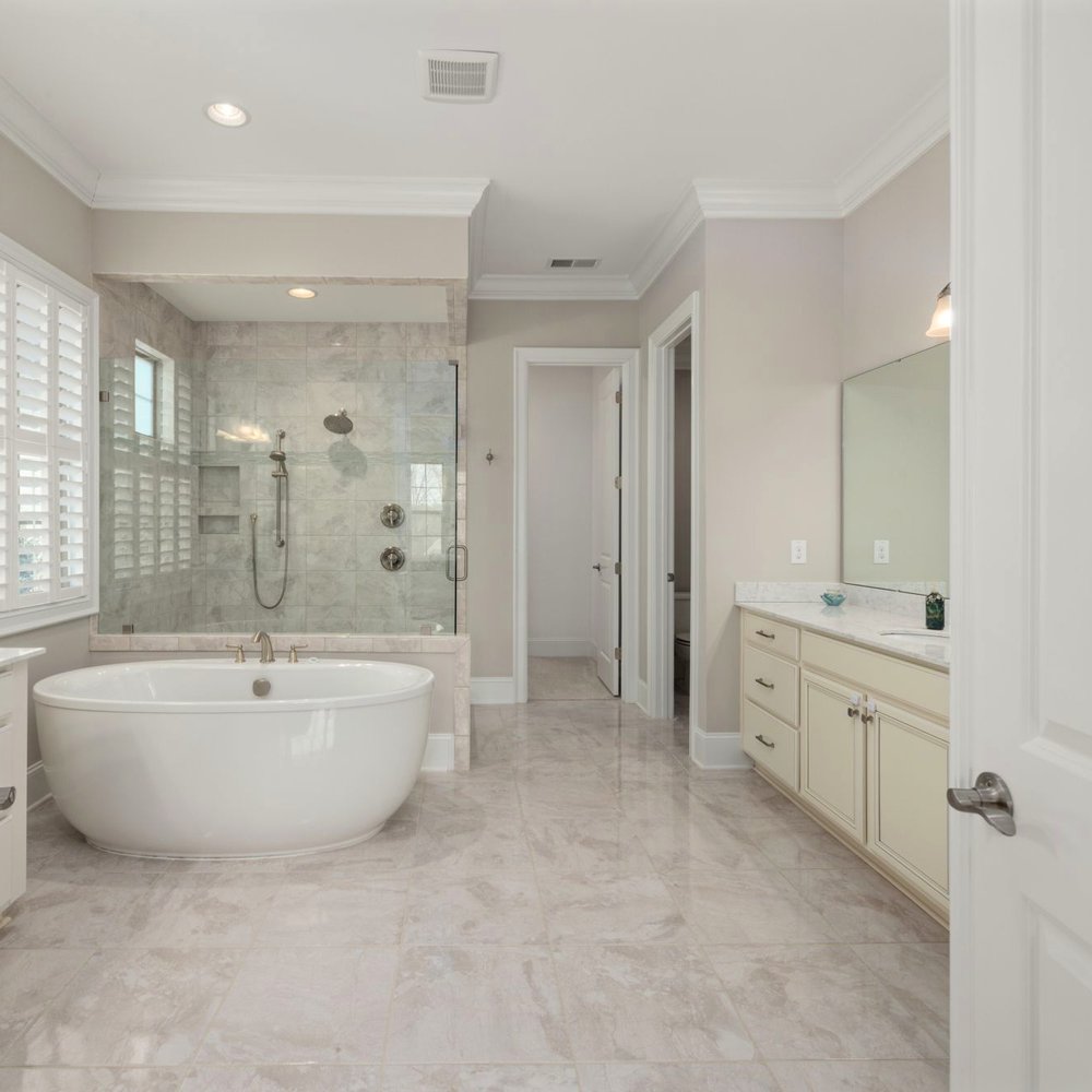 A freestanding spa tub against white marble in a luxury residential bathroom.