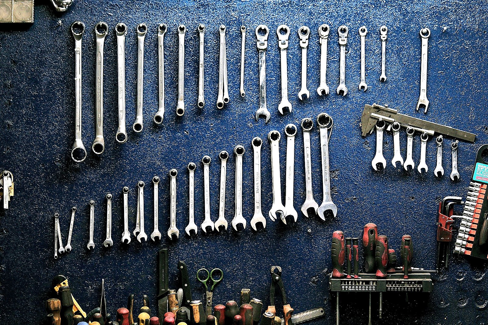 Organized wrenches and shop tools on a deep blue tune-bay wall.