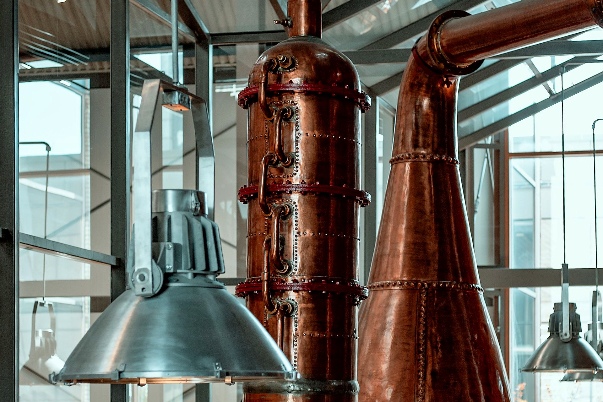 Copper Quill Stillhouse. Bright copper stills under a glass hall roof.