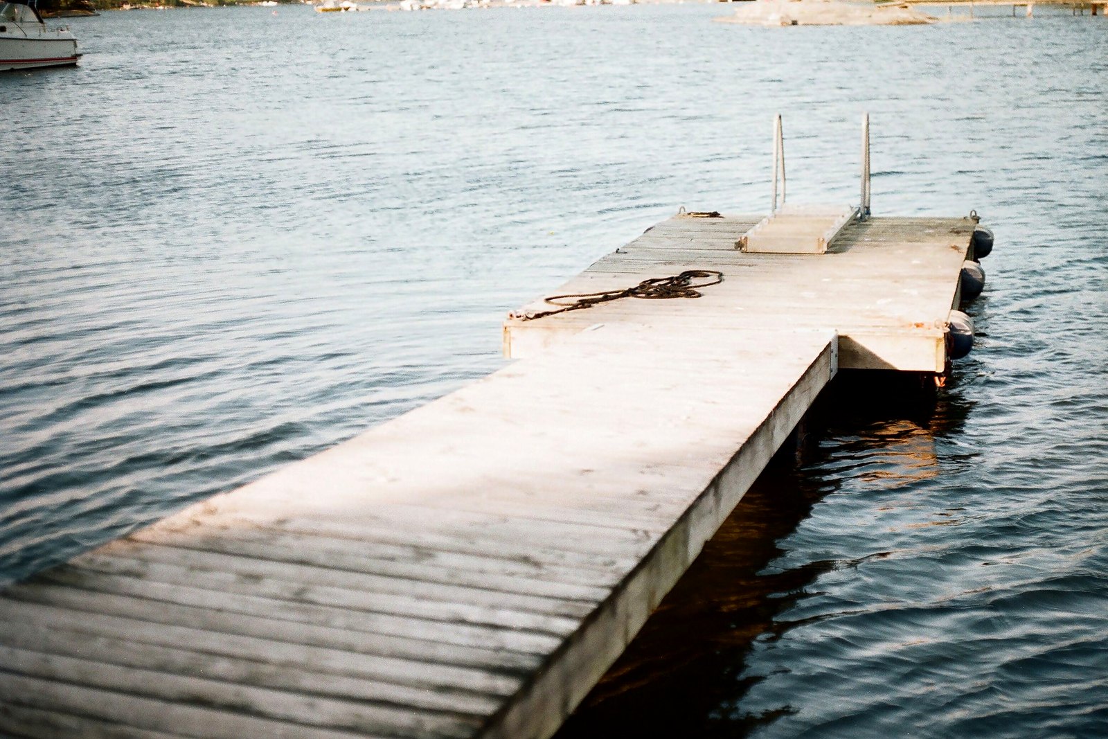 Clean wooden dock with coiled rope on calm silvery lake water.