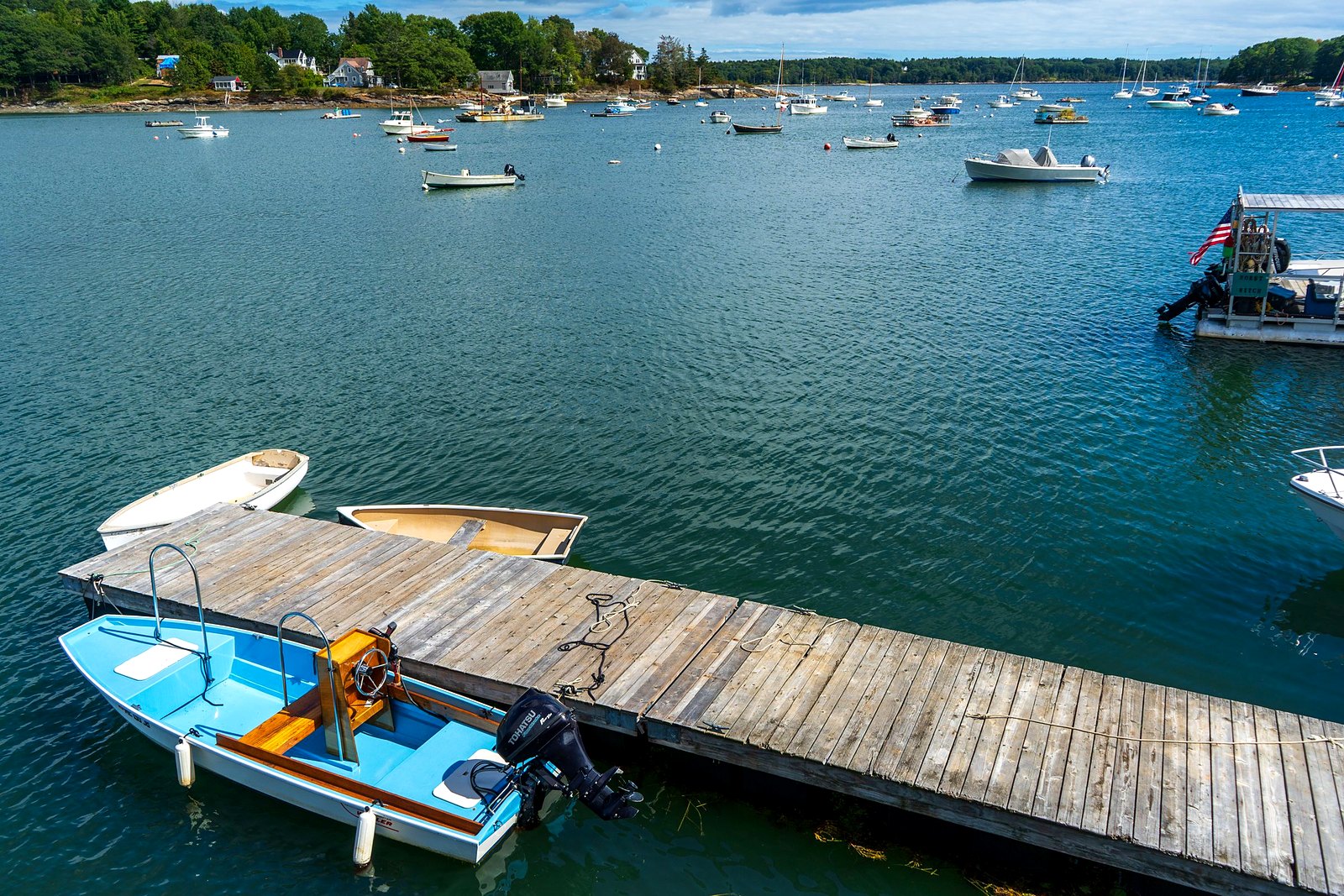 Busy harbor docks with small boats and dinghies tied along wooden piers.