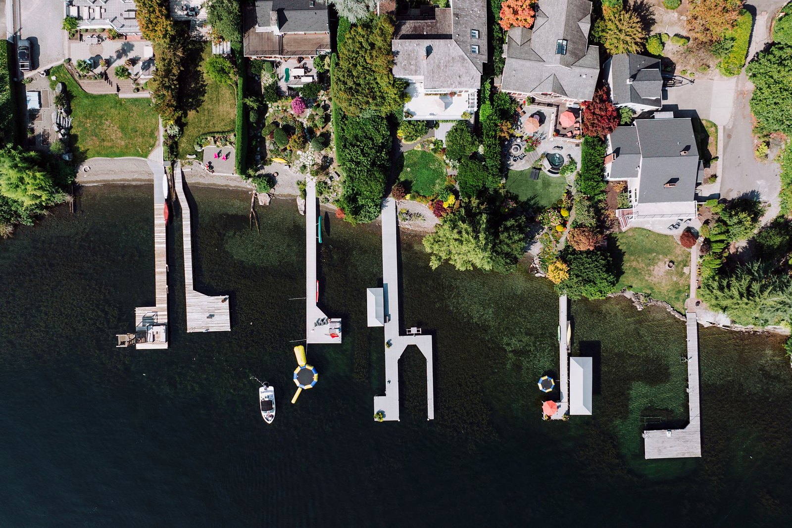 Aerial view of lakeside docks and boat slips among green shoreline trees.