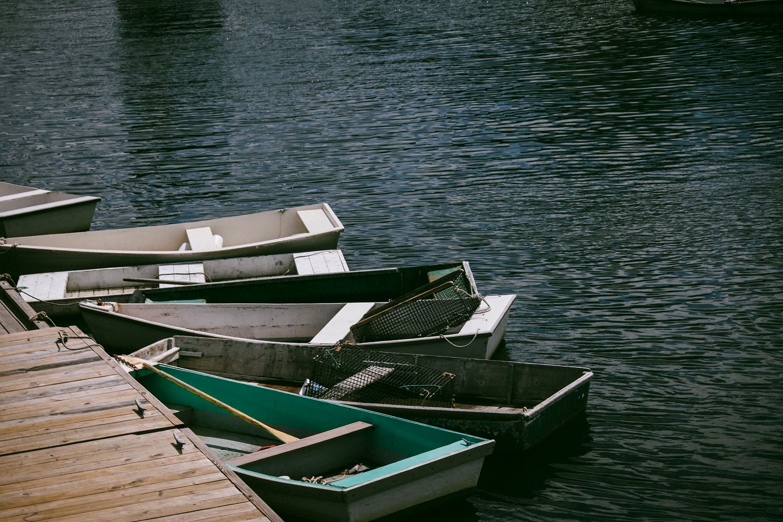 Rustic wooden boats docked along a peaceful tree-lined riverbank.