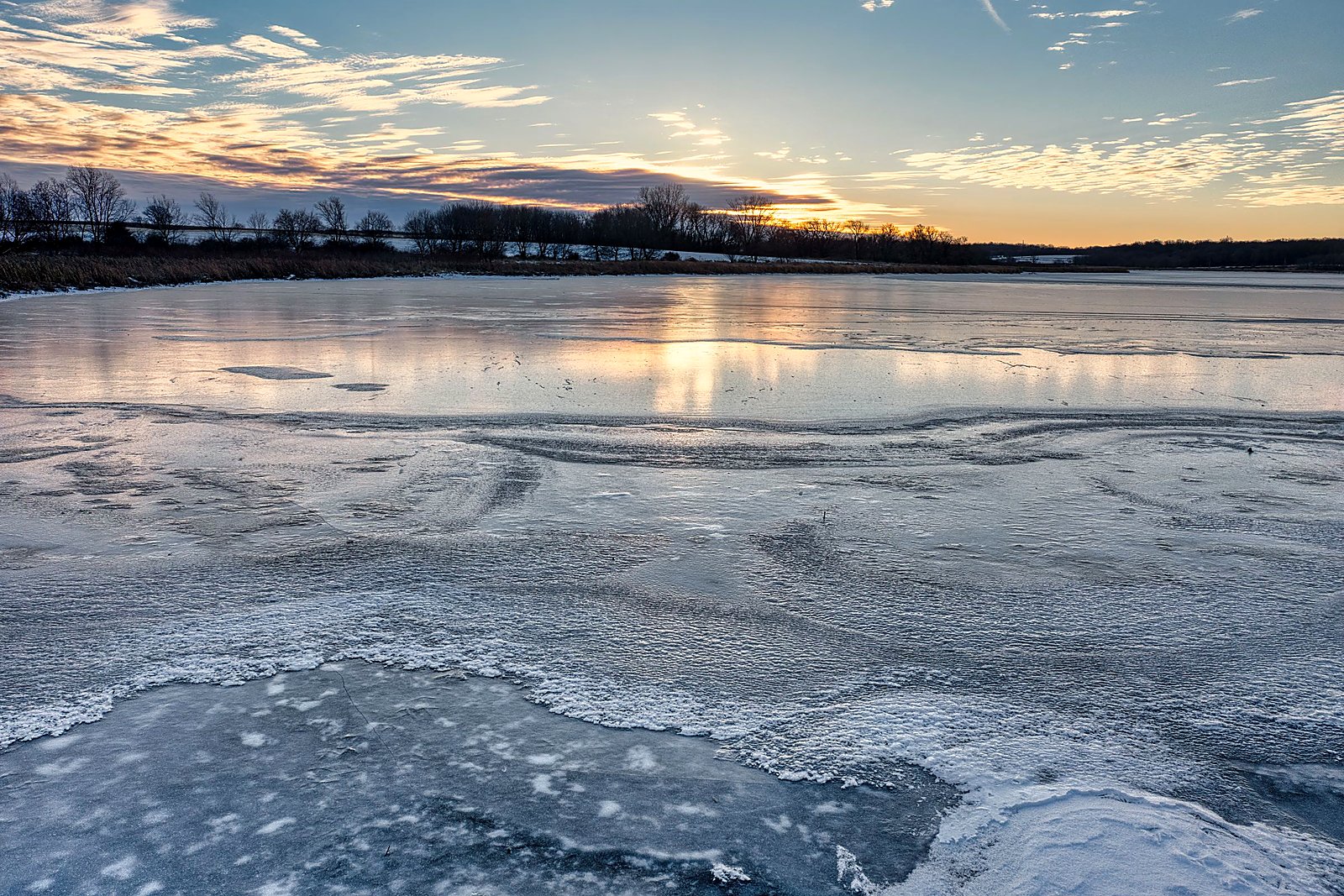 Sunrise light pouring across textured frozen lake ice.