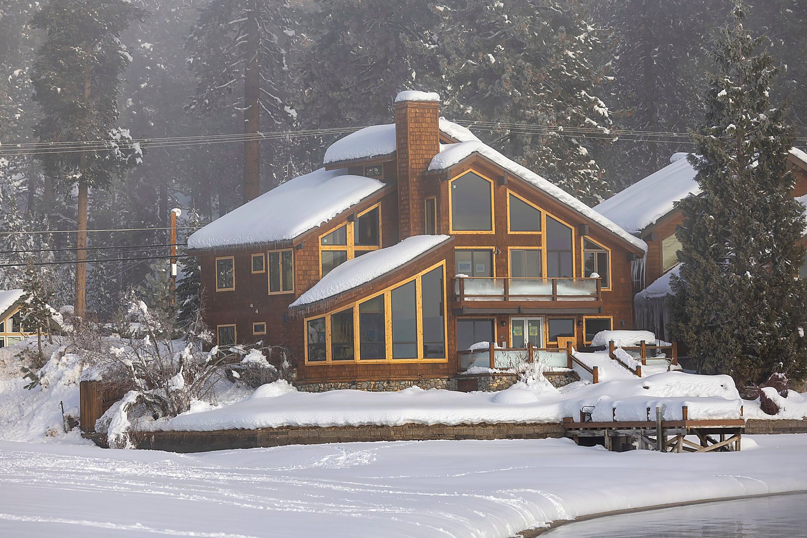 Snow-covered lakeside lodge with warm wood and winter pines.