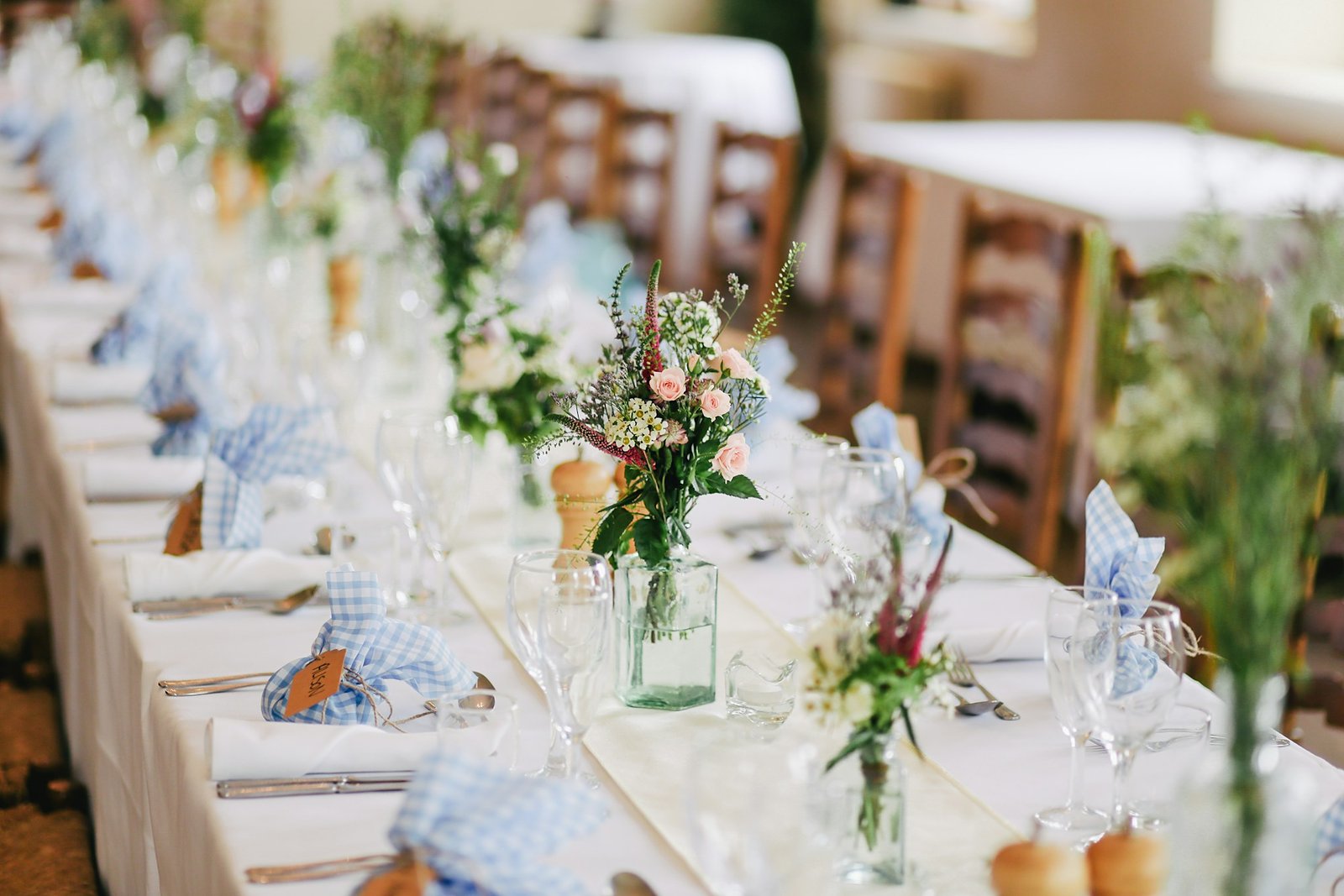 Long reception table with soft florals and place settings.