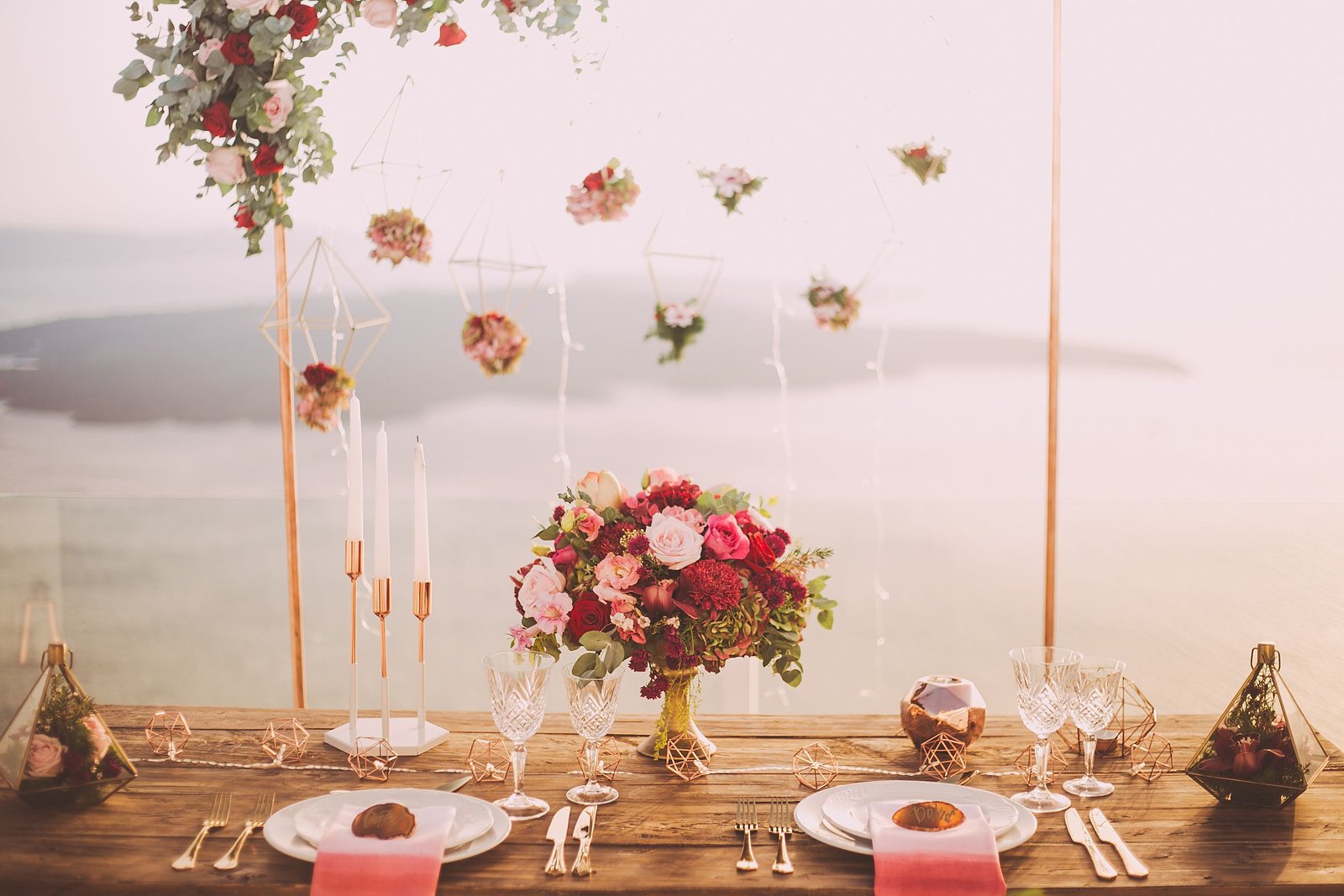 Two-seat table by the water at sunset with flowers and candlelight.