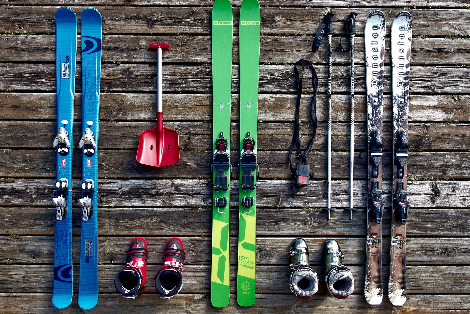 Ski gear laid out on wooden boards — skis, boots, poles.
