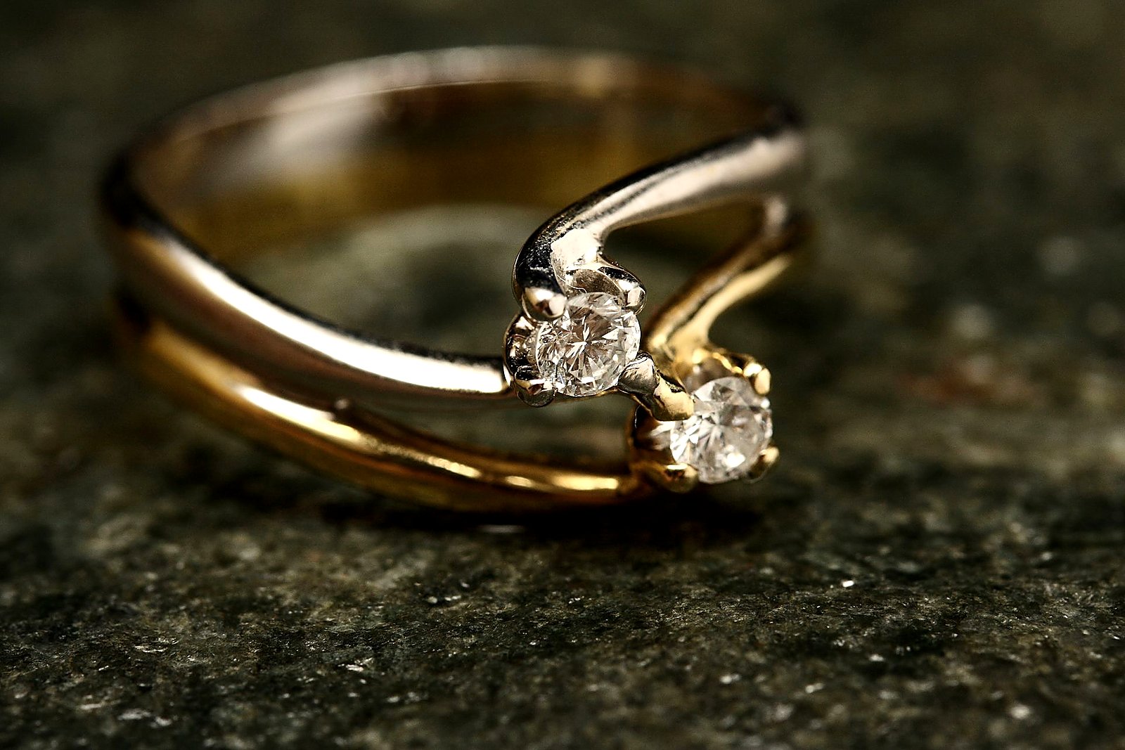 Two-tone bypass ring with paired diamonds on dark stone.