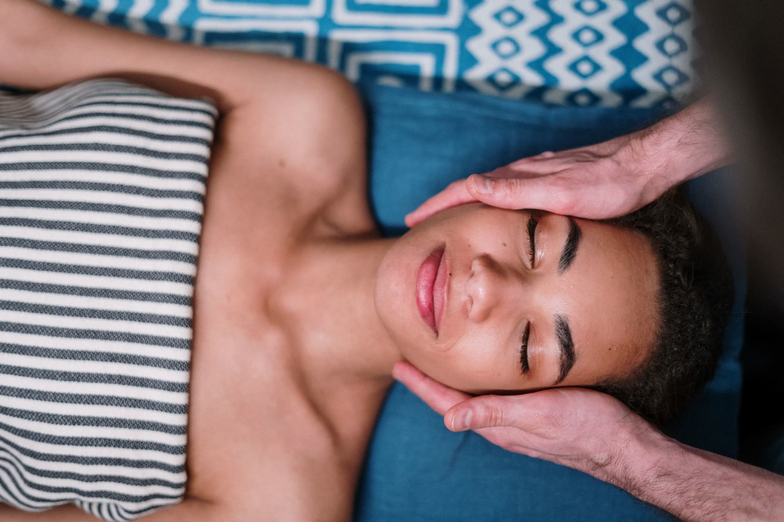 Client resting on the table during gentle face and temple care, professionally draped.