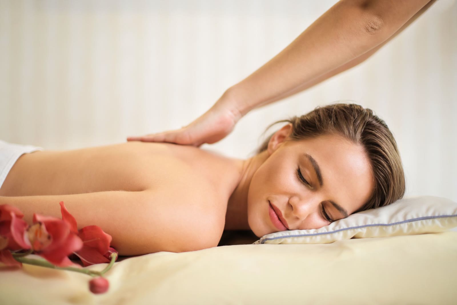 Warming therapeutic massage on the upper back in a cream spa room.